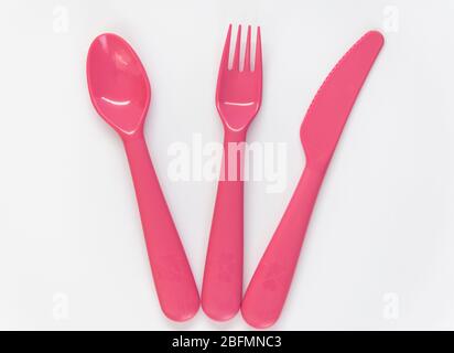 Kunststoff rosa Löffel, Messer und Gabel auf dem weißen Hintergrund. Flaches Lay. Draufsicht. Stockfoto