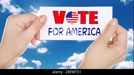Hände halten Stimme für Amerika Karte auf Himmel Hintergrund Stockfoto