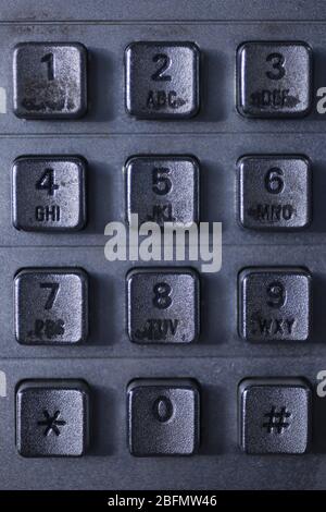 Nahaufnahme einer schmutzigen öffentlichen Telefontastatur aus Metall. Makroansicht der Tasten und Ziffern einer öffentlichen Telefontastatur. Stockfoto