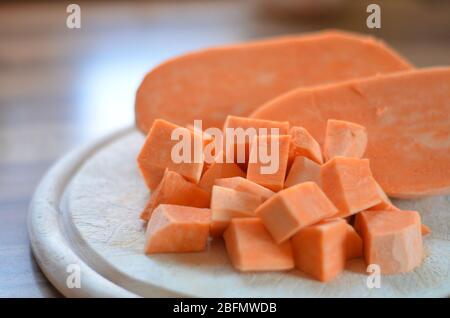 Gewürfelte Süßkartoffeln/Yam/kumara auf einem Schneidebrett in der Küche, Kochen mit gesundem Gemüse Stockfoto