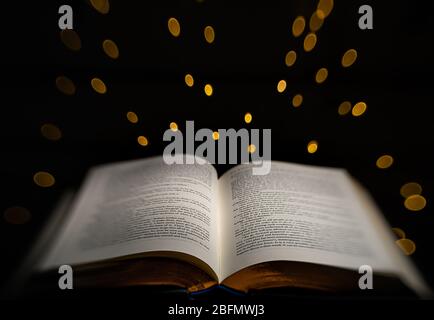 Ein Buch mit goldenen Rändern wird mit leuchtenden Sternenlichtern im Hintergrund hervorgehoben Stockfoto