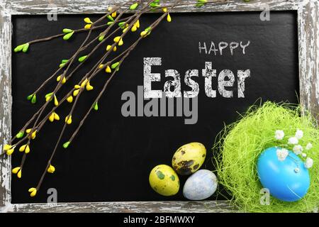 Grußkarte zu Ostern. Bunte Eier mit Ästen auf der Tafel, Draufsicht Stockfoto