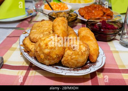 Ein Haufen gebratener, gefüllter polnischer Kroketten, die auf einem dekorierten Tisch liegen, sichtbare Pilze und Rüben. Stockfoto