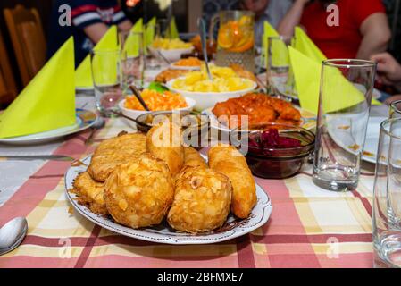 Ein Haufen gebratener, gefüllter polnischer Kroketten, die auf einem dekorierten Tisch liegen, sichtbare Pilze und Rüben. Stockfoto