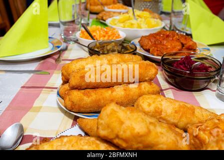 Ein Haufen gebratener, gefüllter polnischer Kroketten, die auf einem dekorierten Tisch liegen, sichtbare Pilze und Rüben. Stockfoto