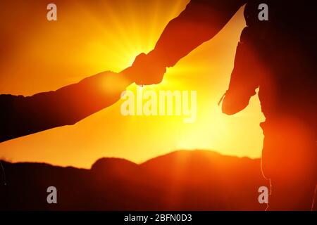 Helfen Hände mit Sonnenlicht zwischen zwei Kletterer Stockfoto