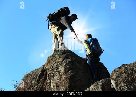 Helfen Hände mit Sonnenlicht zwischen zwei Kletterer Stockfoto