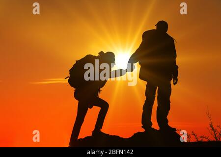 Helfen Hände mit Sonnenlicht zwischen zwei Kletterer Stockfoto