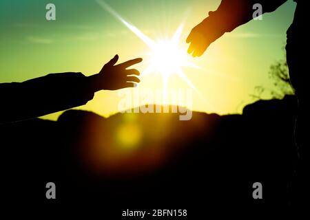 Helfen Hände mit Sonnenlicht zwischen zwei Kletterer Stockfoto