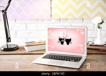 Moderne Lampe und Laptop mit Bildschirmschoner auf dem Tisch auf Backstein Wand Hintergrund Stockfoto