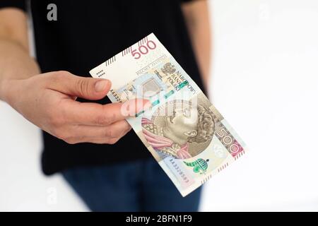 Nahaufnahme einer Banknote im Nennwert von 500 PLN polnisches Geld, Zloty in den Händen einer Frau auf weißem Hintergrund gehalten Stockfoto
