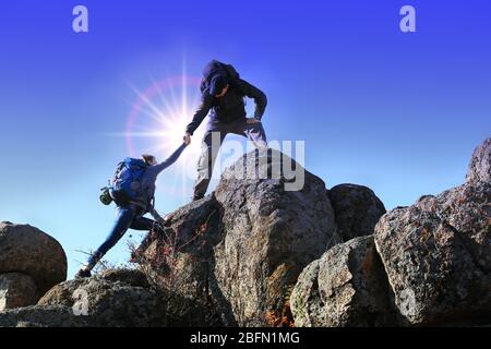 Helfen Hände mit Sonnenlicht zwischen zwei Kletterer Stockfoto