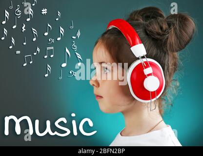 Schönes kleines Mädchen, das Musik auf farbigem Hintergrund hört Stockfoto