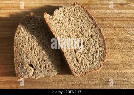 Zwei Scheiben Roggenbrot liegen auf einem Holzbrett. Stockfoto