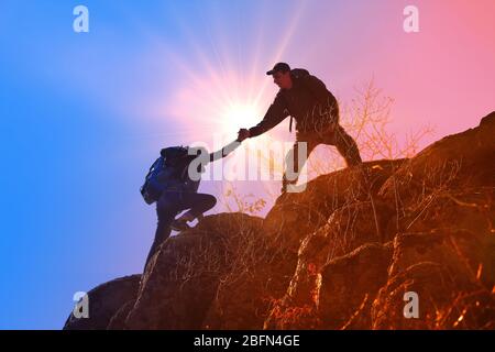 Helfen Hände mit Sonnenlicht zwischen zwei Kletterer Stockfoto