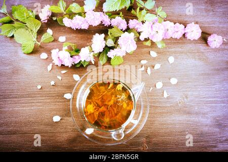 Tasse Tee mit schönen Blumen auf hölzernen Hintergrund Stockfoto