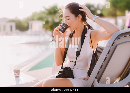 Frau Bloggerin Fotograf trinkt Kaffee im Freien. Frau, die im Freien Kaffee trinkt. Sommerzeit. Stockfoto