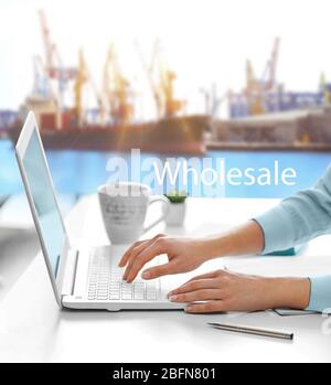 Weibliche Hände arbeiten mit Laptop, Wort GROSSHANDEL auf Port Hintergrund. Transport logistic Konzept. Stockfoto