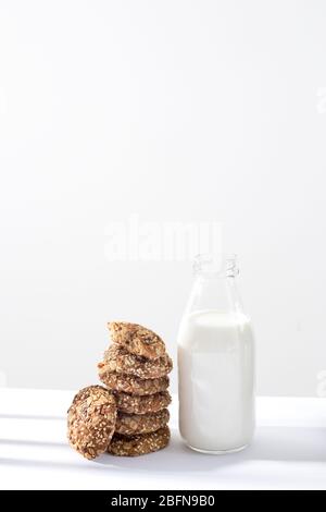 Eine offene Flasche Milch mit Haferflocken, die mit Sesamsamen und Mandeln bestreut sind, auf einem Tisch an einer grauen Wand in der Küche. Kopierbereich Stockfoto