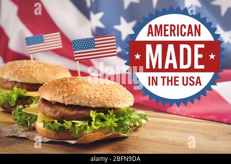 Etikett mit Text AMERICAN MADE IN the USA und leckeren Burgern auf Holztisch. Stockfoto