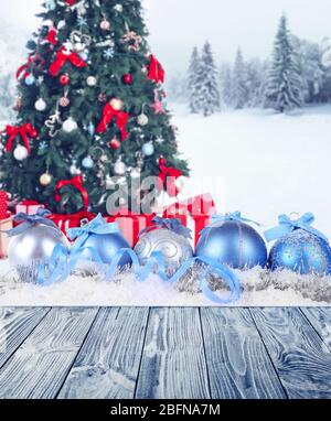 Holztisch und festliche Komposition auf Schnee vor dekorierten Weihnachtshintergrund. Stockfoto
