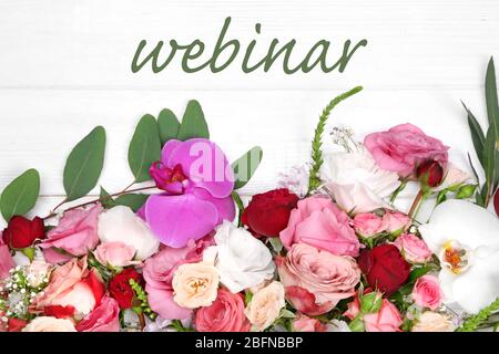 Word WEBINAR und Blumen auf weißem Holzhintergrund. Floristin und Blumendesign Tutorial Konzept. Stockfoto