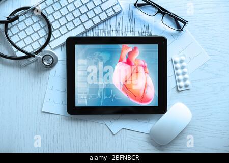 Tablet und Tastatur auf dem Tisch. Herz auf dem Bildschirm. Medizin und modernes Technologiekonzept. Stockfoto