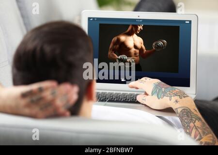 Mann beobachtet Sporttraining online auf Laptop. Fitness und Sport Blog. Stockfoto