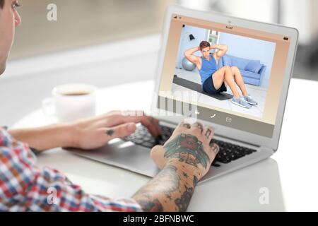 Mann beobachtet Sporttraining online auf Laptop. Fitness und Sport Blog. Stockfoto