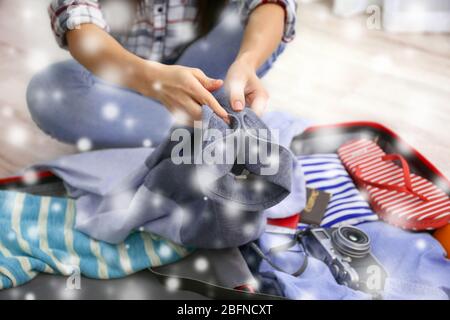 Winterurlaub Konzept. Schnee-Effekt auf Hintergrund. Frau packt Sachen in Koffer zu Hause Stockfoto