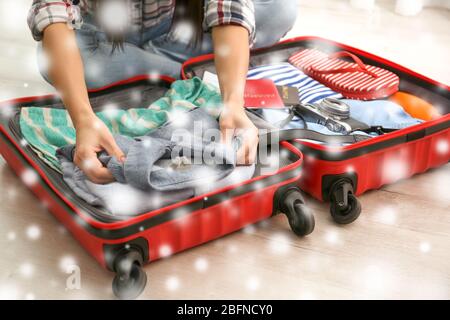 Winterurlaub Konzept. Schnee-Effekt auf Hintergrund. Frau packt Sachen in Koffer zu Hause Stockfoto