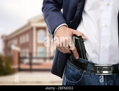 Mann mit Pistole auf Schulhintergrund Stockfoto