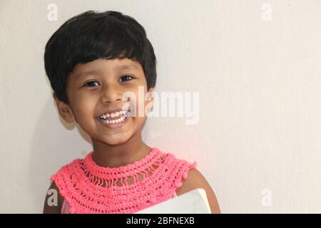 Ein kleines Mädchen mit lächelndem Gesicht und weißem Hintergrund, Dhaka, Bangladesch. Stockfoto