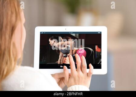 Frau beobachtet Sporttraining online auf Tablet. Fitness und Sport Blog. Stockfoto