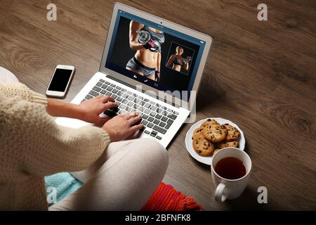 Frau beobachtet Sporttraining online auf dem Laptop. Fitness und Sport Blog. Stockfoto