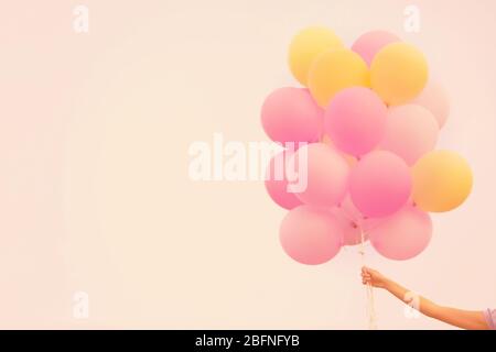 Weibliche Hand hält bunte Ballons vor Himmel Hintergrund Stockfoto