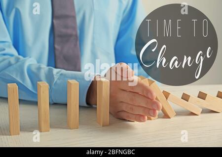 Männliche Hand Stoppen fallenden Dominosteine und Text ZEIT, UM auf Hintergrund ZU ÄNDERN Stockfoto