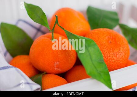 Helle Mandarinen in einem weißen kleinen Kasten auf weißem Hintergrund Stockfoto