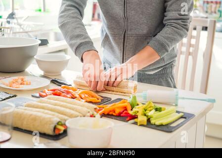 Cropped jungen kaukasischen Mann macht Sushi zu Hause nach dem Kochen Online-Video-Klassen auf der Website über Smartphone. Internet-Technologie für das moderne Leben Stockfoto