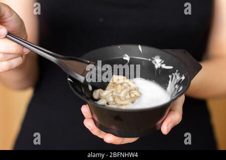 Werkzeuge zum Färben von Haaren in Frauenhänden. Färbung der Haare zu Hause Stockfoto
