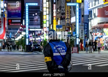 Eine Polizei der Shinjuku Station überredet die Leute, während der Krise von Covid-19 die Straße zu verlassen. Die japanische Regierung hat den Ausnahmezustand ausgerufen, um das ganze Land zu bedecken und wird bis zum 6. Mai andauern. Der Gouverneur von Tokio, Yuriko Koike, hat Restaurants und Bars gebeten, um 20 Uhr als vorbeugende Maßnahme gegen COVID-2019 geschlossen zu werden. Stockfoto