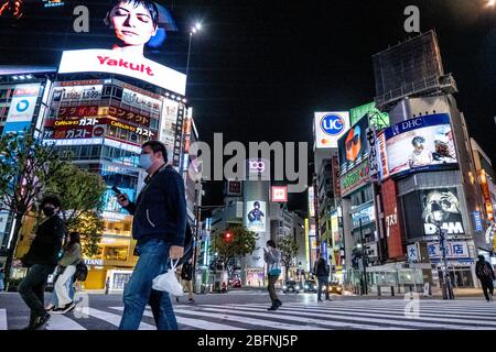 Menschen, die Gesichtsmasken tragen, gehen während der Krise von 19 auf einer fast leeren Straße in Shibuya entlang. Die japanische Regierung hat den Ausnahmezustand ausgerufen, um das ganze Land zu bedecken und wird bis zum 6. Mai andauern. Der Gouverneur von Tokio, Yuriko Koike, hat Restaurants und Bars gebeten, um 20 Uhr als vorbeugende Maßnahme gegen COVID-2019 geschlossen zu werden. Stockfoto