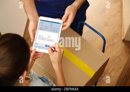 Frau hängt Unterschrift nach Erhalt Paket von Kurier zu Hause Stockfoto