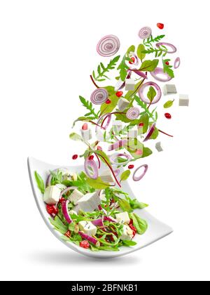 Zutaten fallen in Schüssel mit Salat auf weißem Hintergrund Stockfoto
