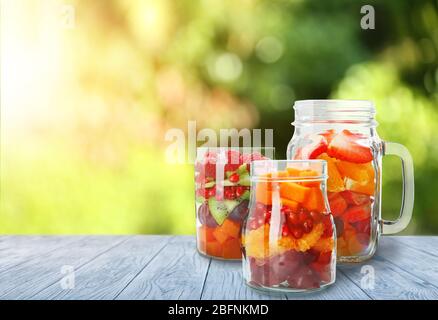 Gläser mit leckeren Salaten auf dem Tisch im Freien Stockfoto