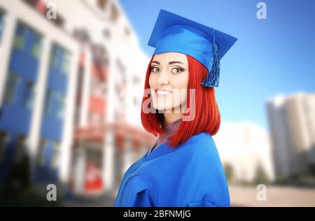 Student in Graduation Kleid und Mütze auf Campus-Gebiet Stockfoto