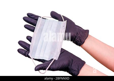 Weibliche Hände in Handschuhen halten eine Maske. Coronovirus-Pandemie Stockfoto