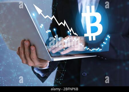 Bitcoin Rate und Geschäftsmann mit Laptop auf farbigen Hintergrund Stockfoto
