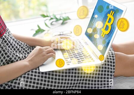 Bitcoin-Symbole und Frau mit Laptop zu Hause Stockfoto