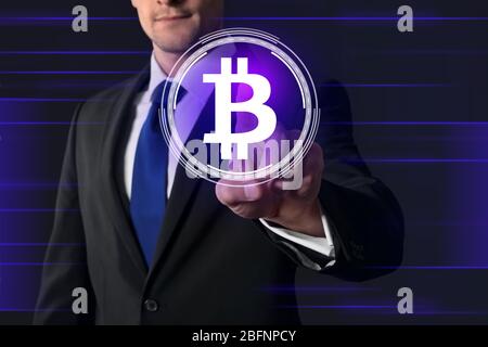 Geschäftsmann drücken Taste mit Bitcoin-Sympol auf virtuellen Bildschirm vor dunklem Hintergrund Stockfoto